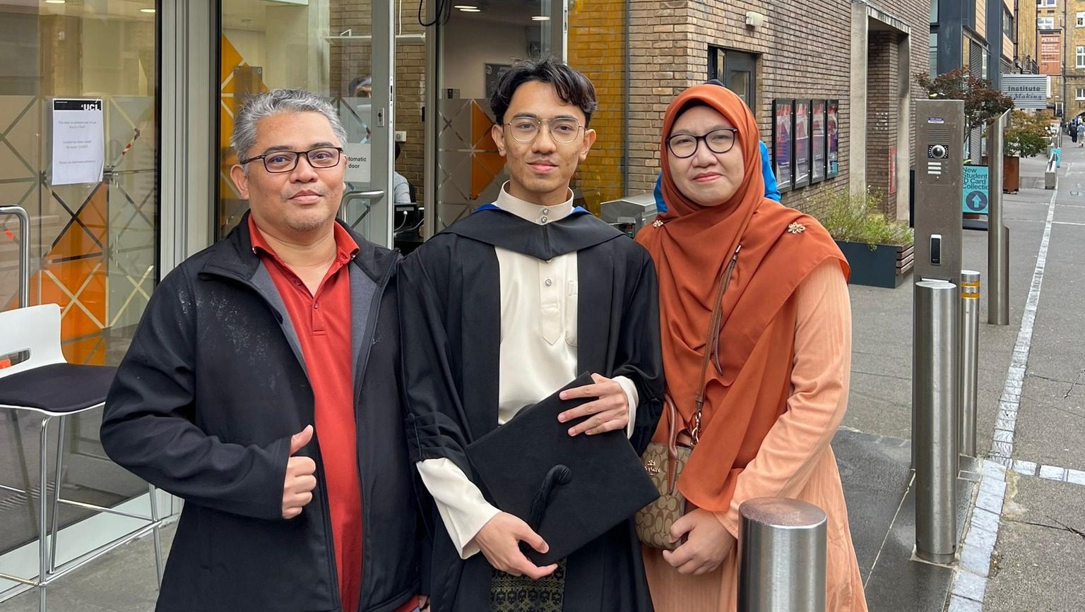 Muhammad Asyraf Hakim bin Zulkifli bersama ibu bapa di hadapan UCL Engineering selepas menamatkan pengajian Master of Electronic & Electrical Engineering dengan First Class Honours.