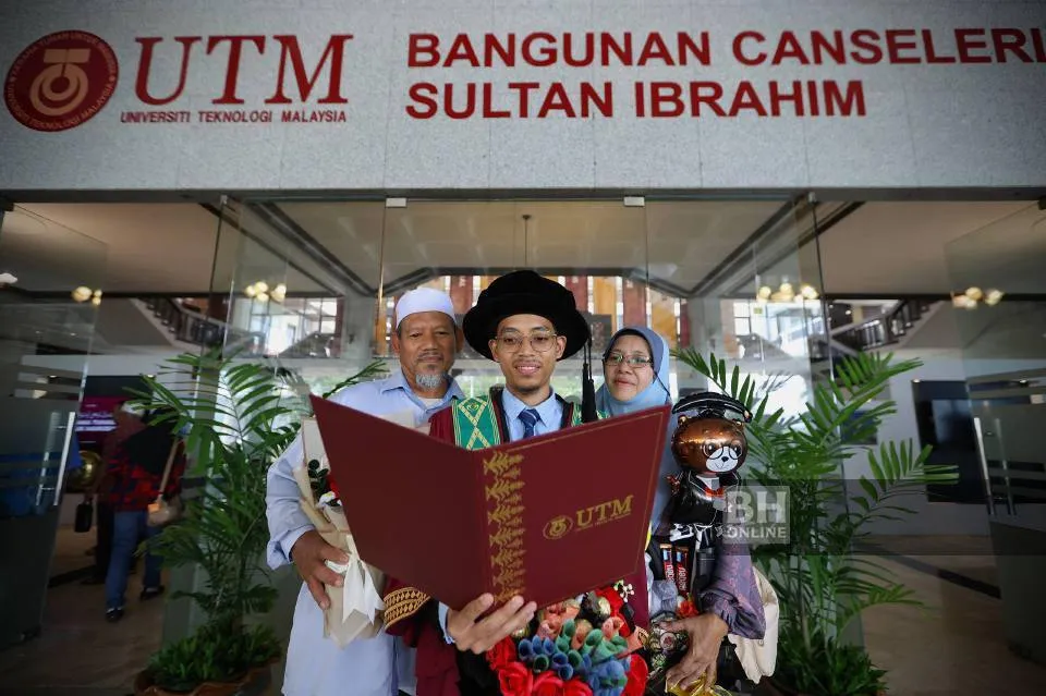 Graduan UTM bergambar bersama keluarga sambil memegang skrol
