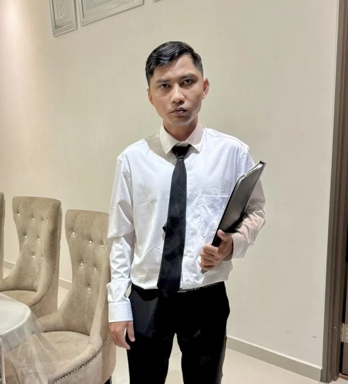 Seorang lelaki muda berpakaian formal memegang fail, berdiri di dalam bilik sebagai simbol usaha gigih menghadapi peperiksaan berkali-kali