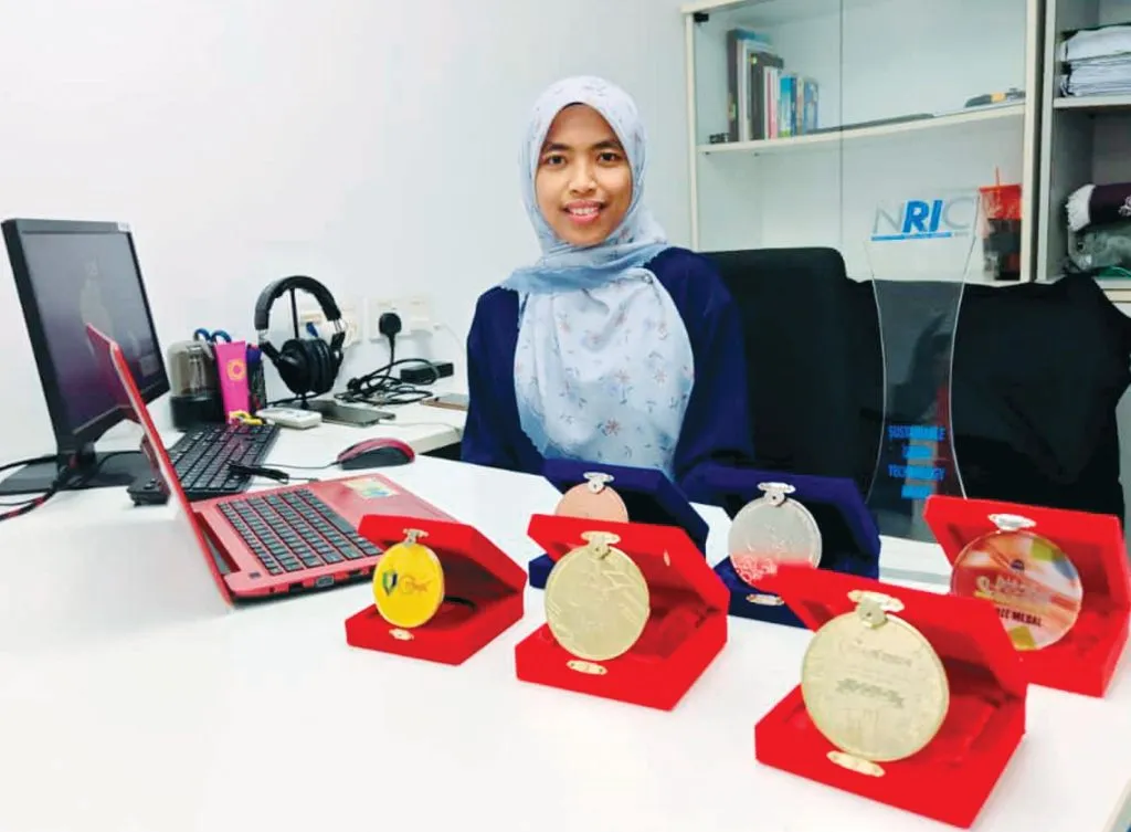 Graduan TVET wanita mempamerkan beberapa pingat dan anugerah di atas meja pejabat.