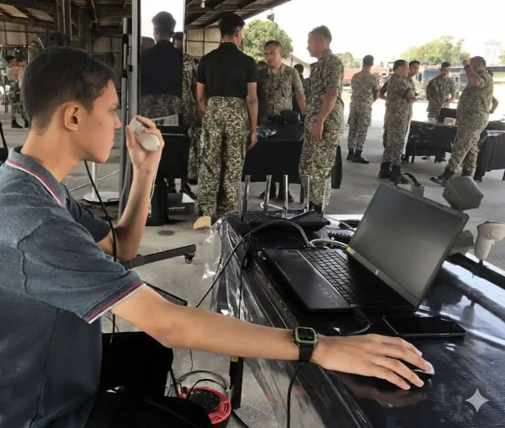 Remaja Malaysia berbakat dalam teknologi bekerja di meja komputer dengan rakan di makmal mini.