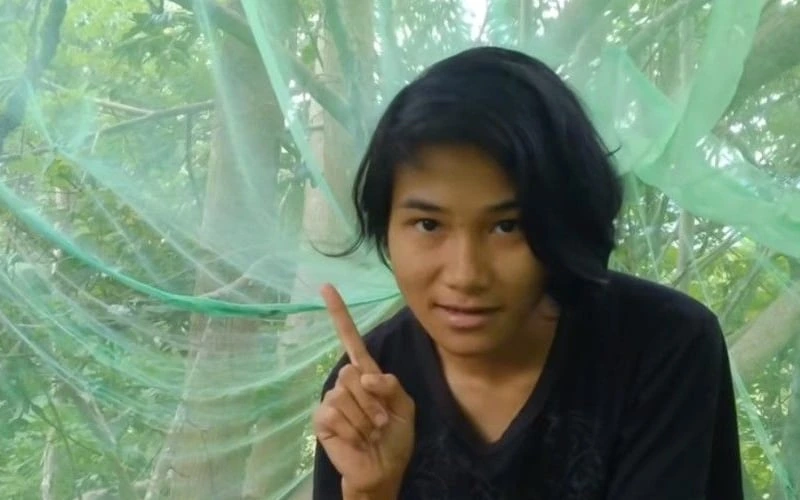 Veveonah Mosibin, pelajar Sabah yang tular kerana memanjat pokok untuk mendapatkan isyarat internet, sedang berada di atas pokok yang ditutup jaring nyamuk sambil menunjukkan jari telunjuknya ke atas, melambangkan perjuangan dalam pendidikan.