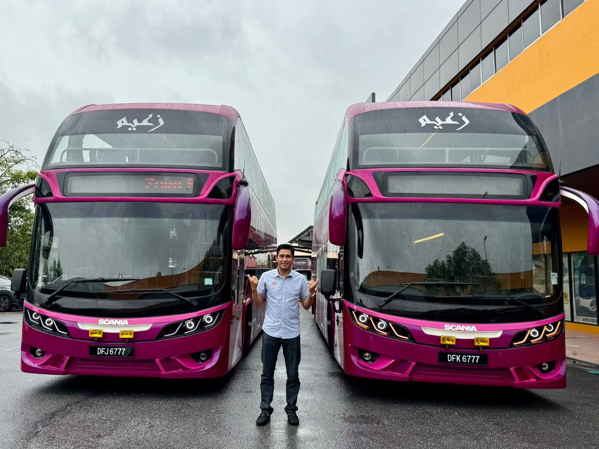 Pengasas Zaim Ekspres berdiri di antara dua buah bas ekspres dua tingkat Scania sempena pengembangan armada