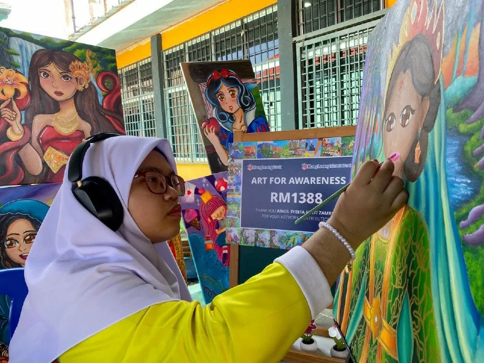 Ainul Syeefa sedang melukis karya seni berwarna-warni di atas kanvas
