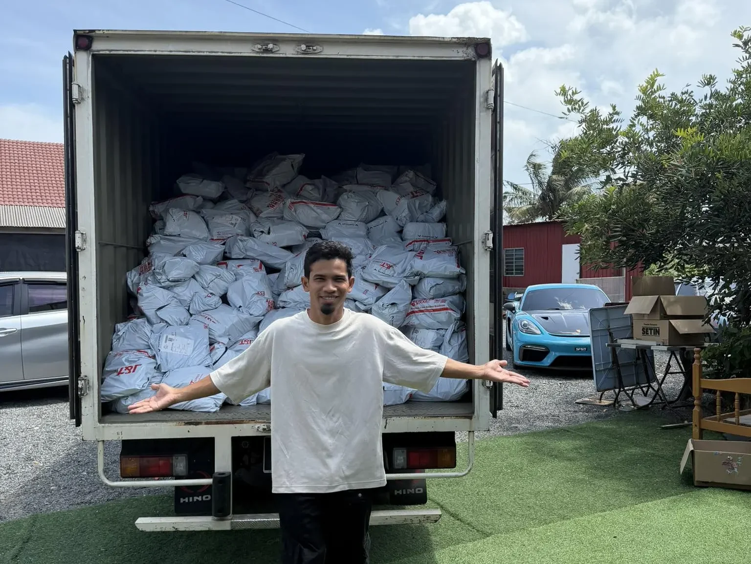 Sukri Sulaiman berdiri di depan lori penuh parcel dengan tangan terbuka