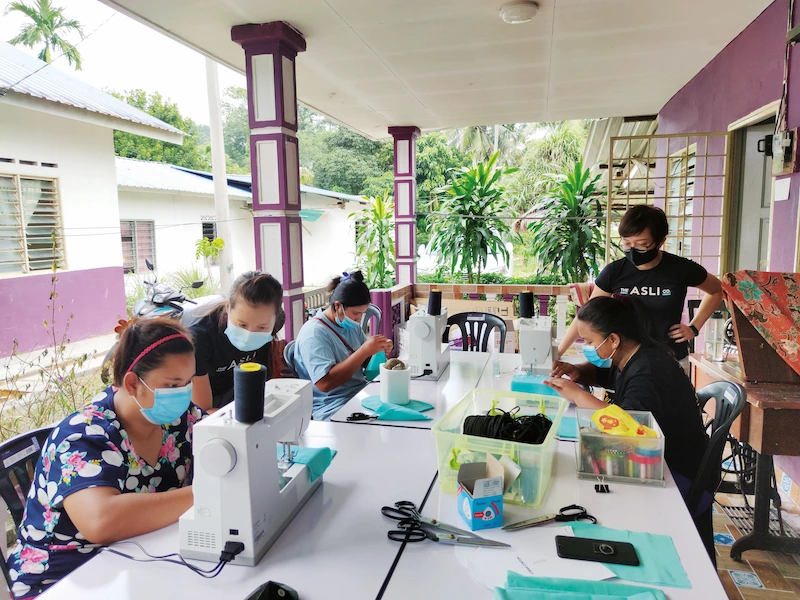 Ibu Orang Asli menjahit produk kraf bersama pasukan The Asli Co dalam program keusahawanan komuniti di Selangor