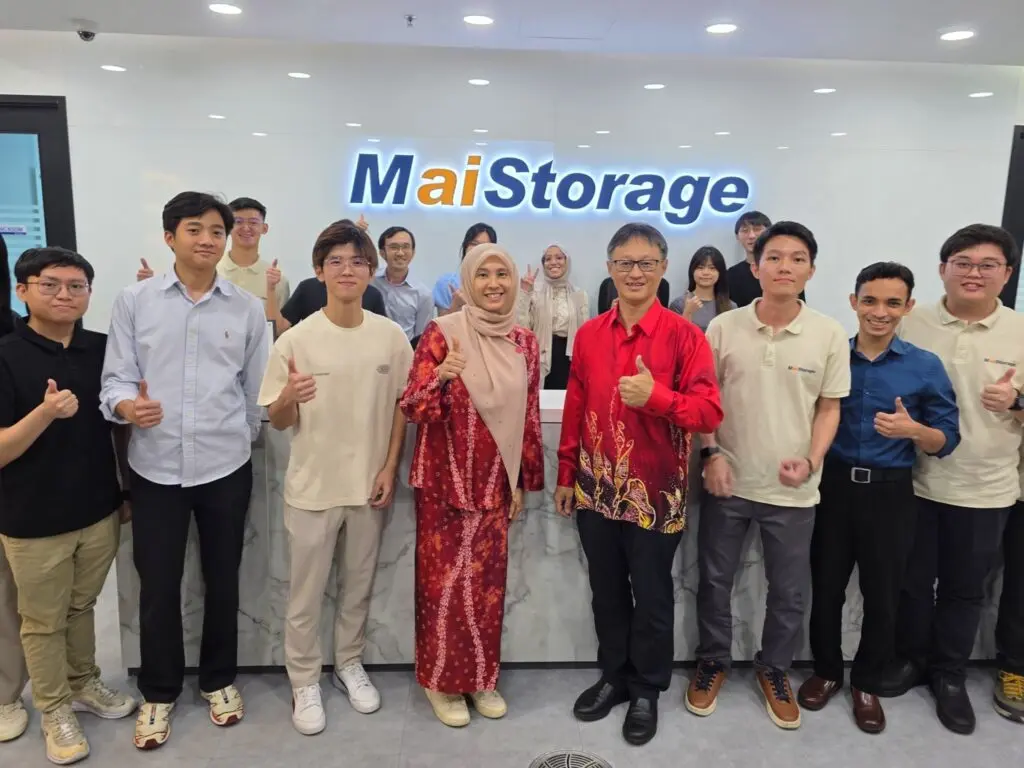 Kakitangan MaiStorage bergambar di hadapan logo syarikat di pejabat
