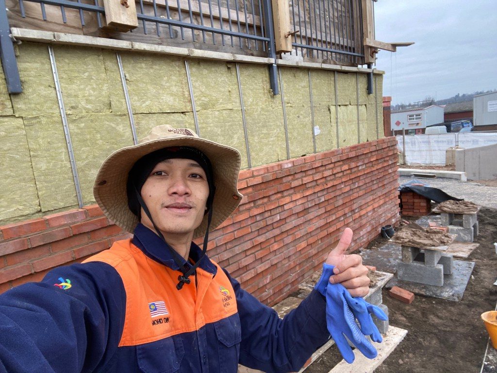 Muhammad Din bricklayer Malaysia UK sedang membina dinding bata di tapak pembinaan London
