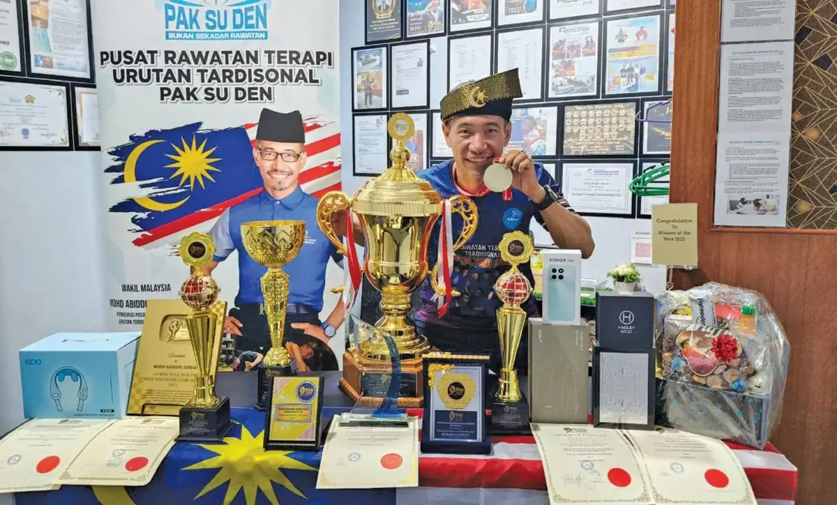 Pak Su Den bergambar bersama trofi dan anugerah kemenangan dalam pertandingan urutan antarabangsa