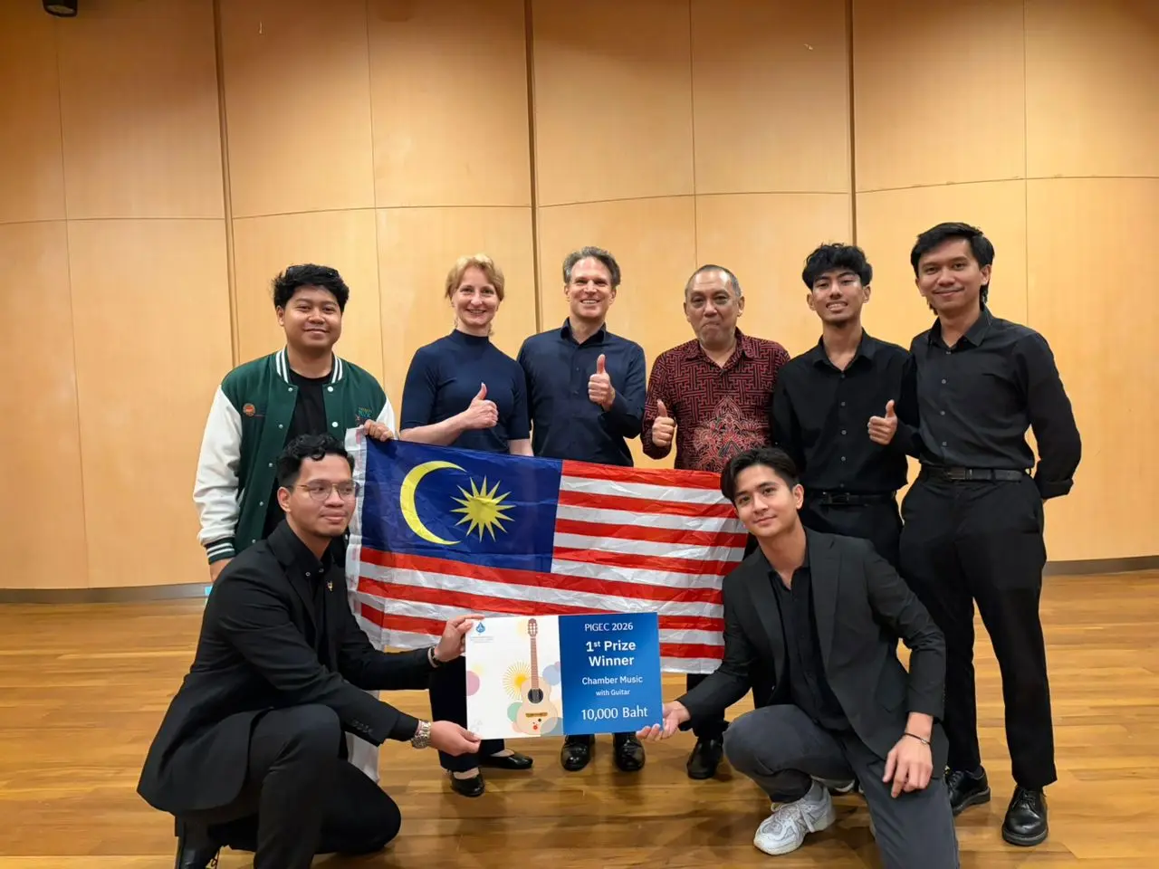 Pelajar UPSI memegang bendera Malaysia selepas menang tempat pertama pertandingan gitar antarabangsa di Bangkok